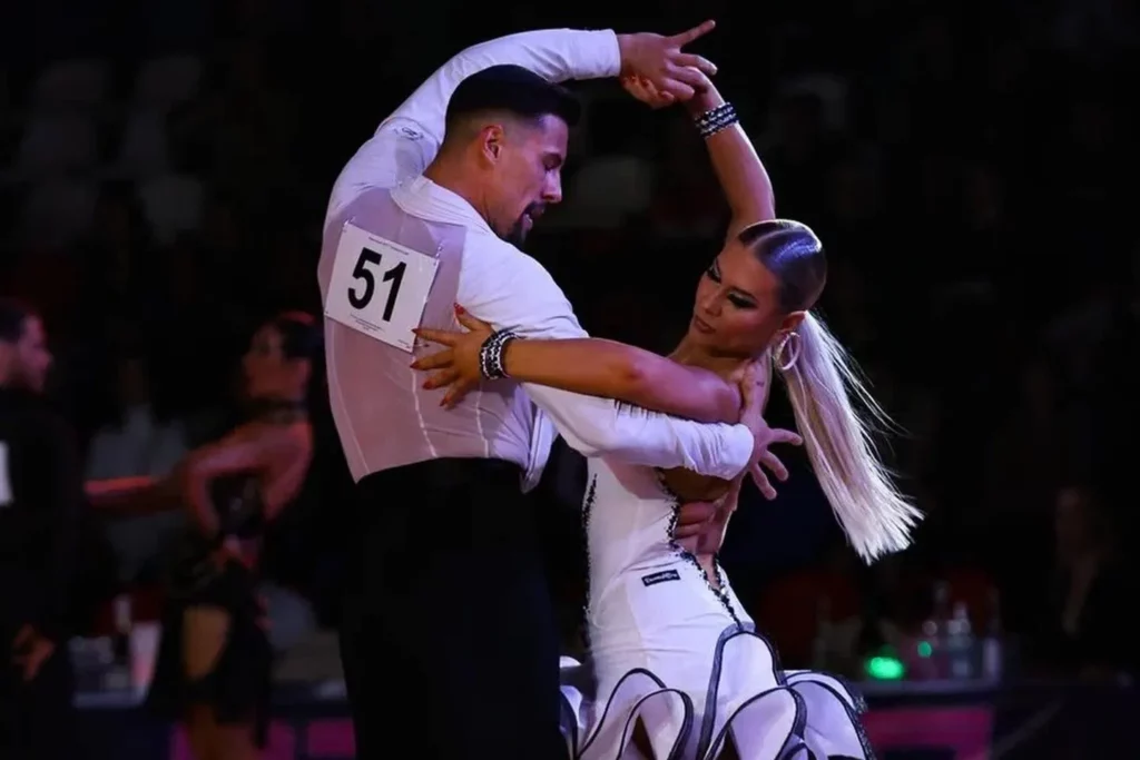 Profesjonalista tańczy z amatorką na konkursie PROAM tańca towarzyskiego. W szkole tańca DanceZone przykłada się dużo uwagi do jakości ruchu i profesjonalnego nauczania.